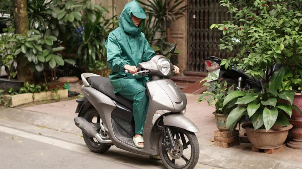 Ảnh tư liệu người mặc bộ áo mưa xanh lục ngồi trên xe máy đang dừng