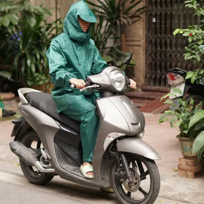 Ảnh tư liệu người mặc bộ áo mưa xanh lục ngồi trên xe máy đang dừng