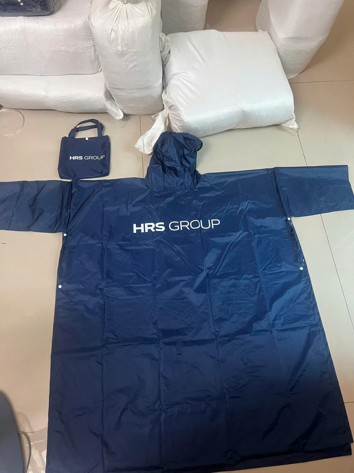 Áo mưa navy và túi có quai cùng dòng chữ trắng trong ảnh nguồn