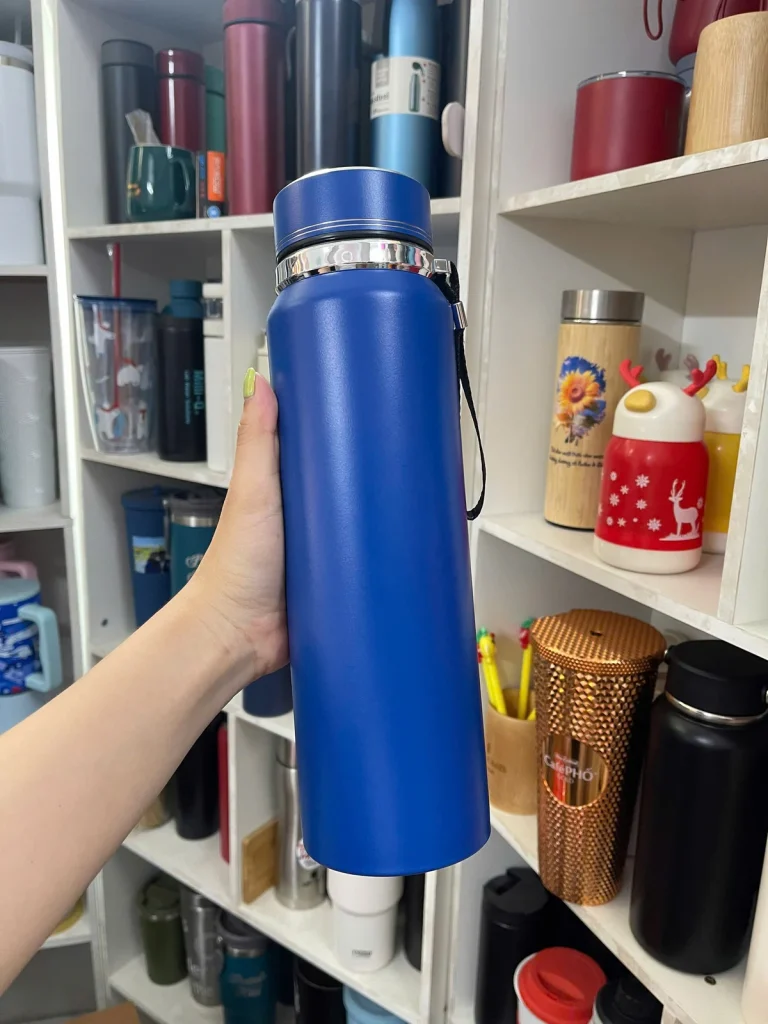 Bình giữ nhiệt xanh dương thân cao được cầm trên tay