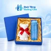 Minh họa bình nhựa xanh dương và khăn gấu cotton trắng nơ đỏ đủ hai món trong hộp xanh lót lụa vàng