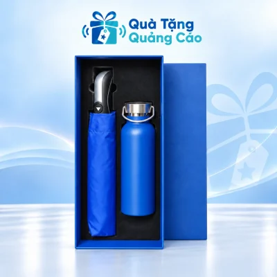 Minh họa đủ bộ trong hộp xanh khay đen: dù xanh bên trái với cán đen bạc, bình quai xách xanh bên phải