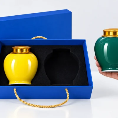 Minh họa một tay đỡ đáy hũ xanh ngoài hộp, ngăn phải đã trống và hũ vàng vẫn trong hộp