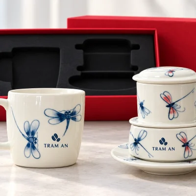 Minh họa logo hạt cà phê TRAM AN trên khoảng trống của cốc lùn và cốc riêng thuộc bộ phin