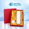 Minh họa bình nhựa trắng, bút bạc phối đỏ và móc mica tròn đủ ba món trong hộp đỏ lót lụa vàng trên nền thương hiệu