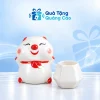 Minh họa một heo đất bánh bao trắng đỏ và một cốc sứ trắng dáng kim cương rỗng trên nền xanh nhạt