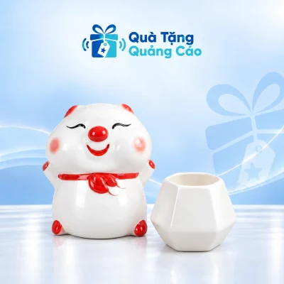 Minh họa một heo đất bánh bao trắng đỏ và một cốc sứ trắng dáng kim cương rỗng trên nền xanh nhạt