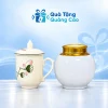 Minh họa hũ trà men trắng nắp đồng vàng và cốc sen men kem có nắp trên nền xanh nhạt