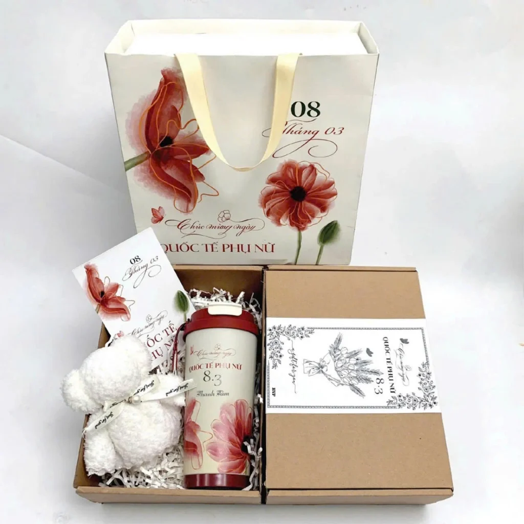Ảnh tư liệu ly nắp đỏ, khăn gấu trắng và thiệp trong hộp carton, túi giấy 8/3 phía sau