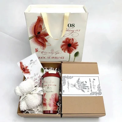 Ảnh tư liệu ly nắp đỏ, khăn gấu trắng và thiệp trong hộp carton, túi giấy 8/3 phía sau