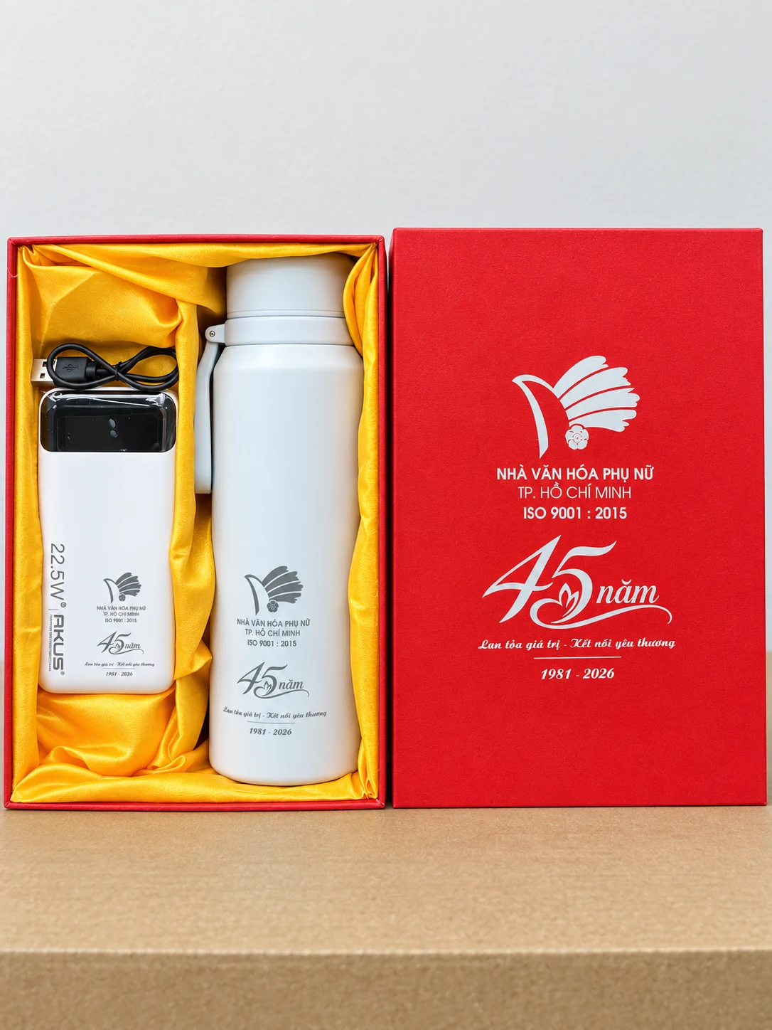 Hộp đỏ chứa hai vật phẩm trắng và dây cáp, giữ phần in nhận diện nguồn