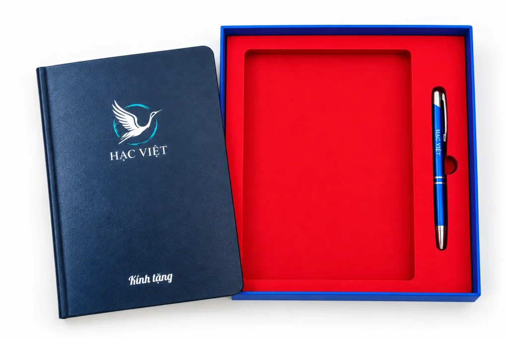 Minh họa sổ in UV HẠC VIỆT đặt cạnh hộp, bút xanh in một màu nằm trong ô bên phải
