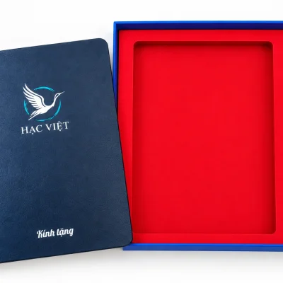 Minh họa sổ in UV HẠC VIỆT đặt cạnh hộp, bút xanh in một màu nằm trong ô bên phải