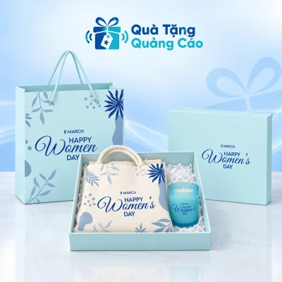 Minh họa túi cói gấp cùng cốc nến xanh nằm trong hộp quà, kèm túi giấy trên nền Quà Tặng Quảng Cáo