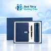 Minh họa sổ A5 xanh tai gài tròn, bút đen viền vàng và bình xanh trong hộp khay sáng