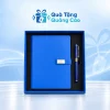 Minh họa sổ xanh trơn tai gài mặt chữ nhật và bút xanh phối vàng trong hộp viền xanh khay đen trên nền thương hiệu