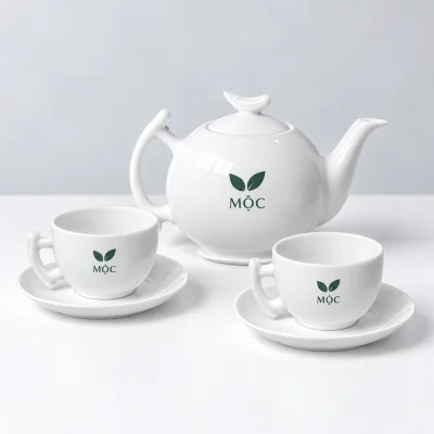 Mô phỏng biểu tượng lá và tên MỘC màu xanh trên ấm và chén men trắng