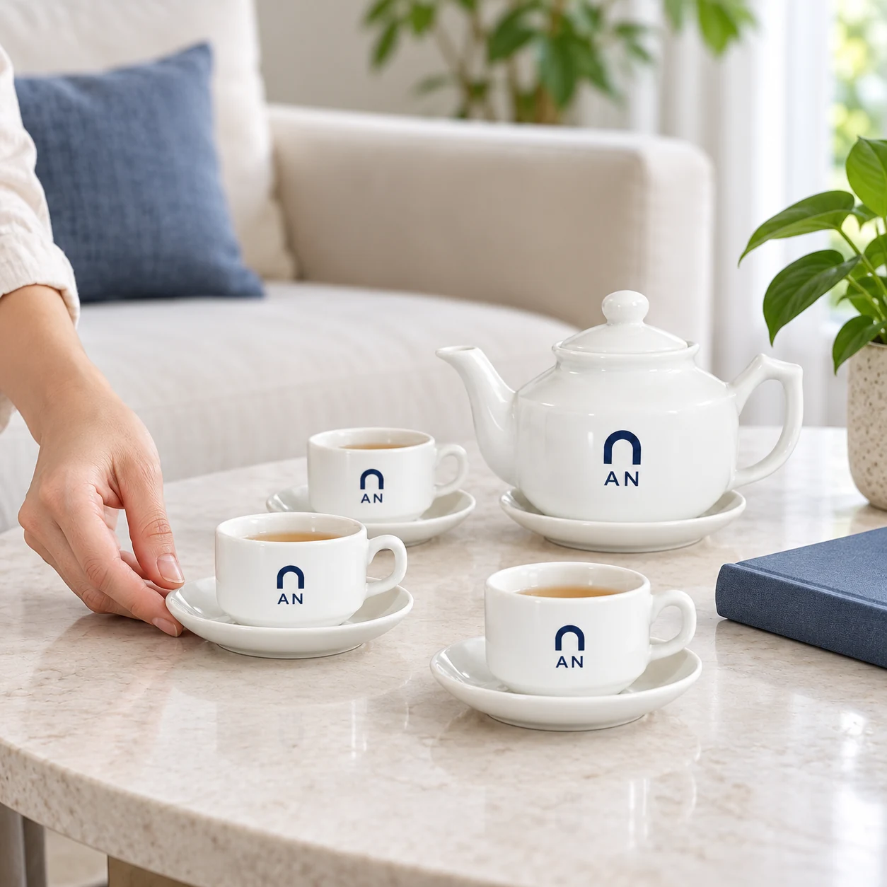 Minh họa một phần bộ trà trắng vuông thấp có logo AN tại góc tiếp khách Minh họa một phần bộ trà trắng vuông thấp có logo AN tại góc tiếp khách