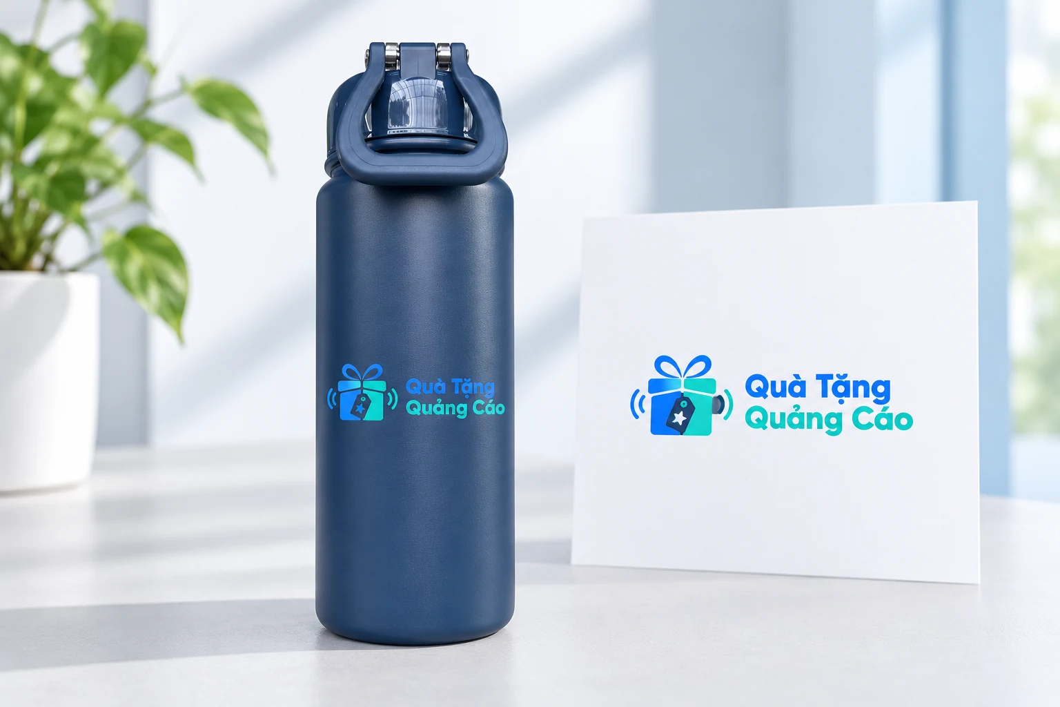 Logo Quà Tặng Quảng Cáo minh họa trên bình xanh có quai nắp cùng bản bố trí