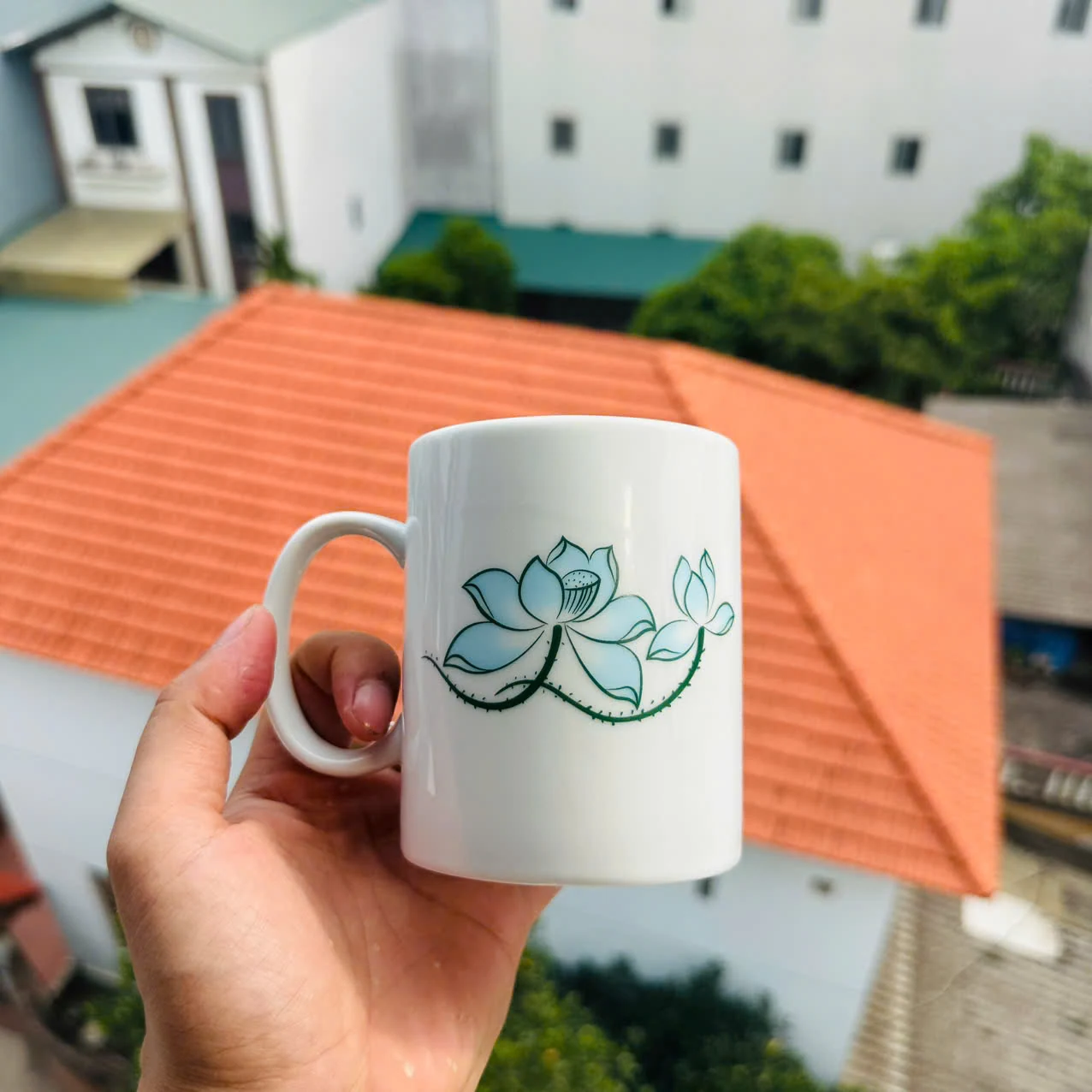 Cốc trắng họa tiết sen đang mở, có quai phía trái trong ảnh nguồn