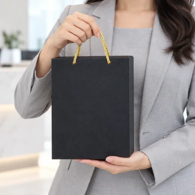 Minh họa cầm hộp đen có quai dây vàng, tay còn lại đỡ đáy