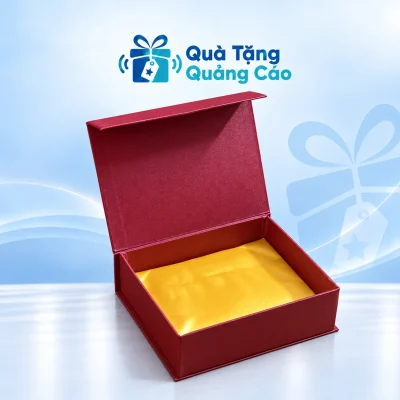 Hộp quà đỏ rượu mở nắp gập, lòng lót vàng trên nền Quà Tặng Quảng Cáo