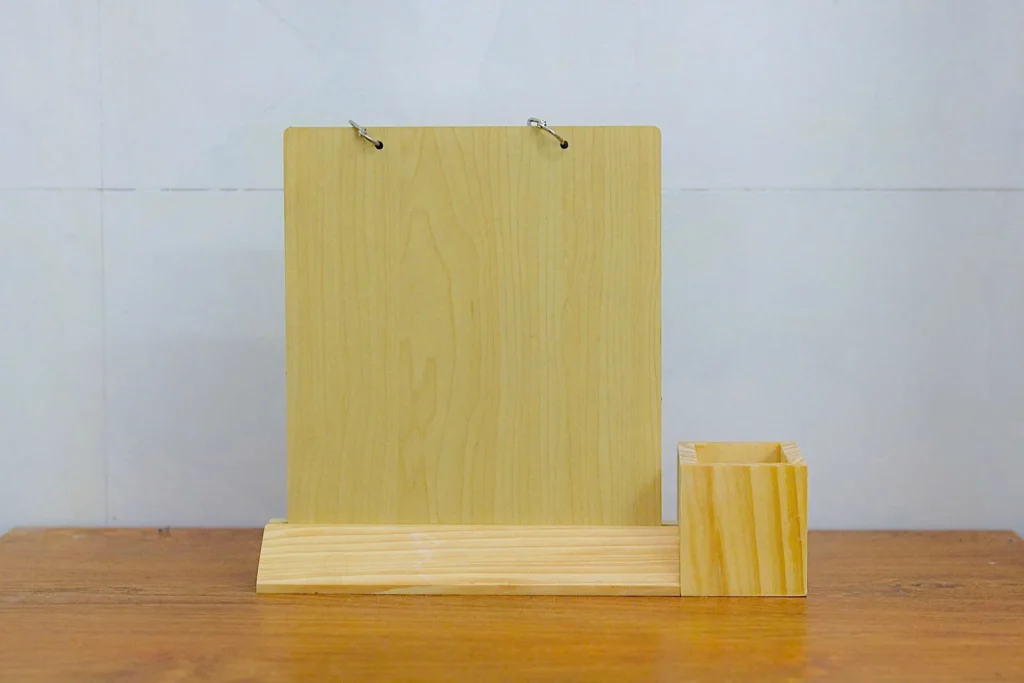 Mặt sau lịch gỗ với hai khoen kim loại và ống bút trên cùng đế