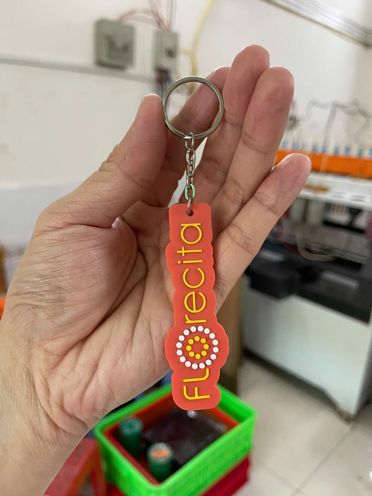 Ảnh tư liệu móc khóa cao su cắt theo chữ Bàn tay cầm móc khóa cao su cam có đường viền theo chữ, chữ nổi vàng trắng và khoen tròn