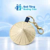 Một móc khóa nón lá màu tự nhiên với dây xanh đậm và khoen móc trên nền Quà Tặng Quảng Cáo