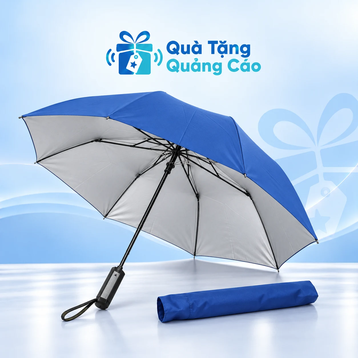 Ô gấp hai 2F108TN trên nền xanh nhạt Ô gấp hai tán xanh mặt trong sáng, tay cầm đen và bao vải đồng màu trên nền Quà Tặng Quảng Cáo