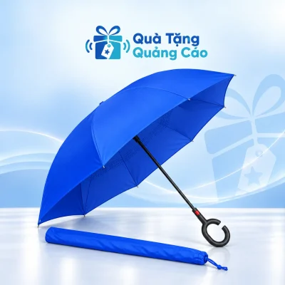Ô gấp ngược tán xanh và tay cầm chữ C đen cùng bao vải đồng màu trên nền Quà Tặng Quảng Cáo