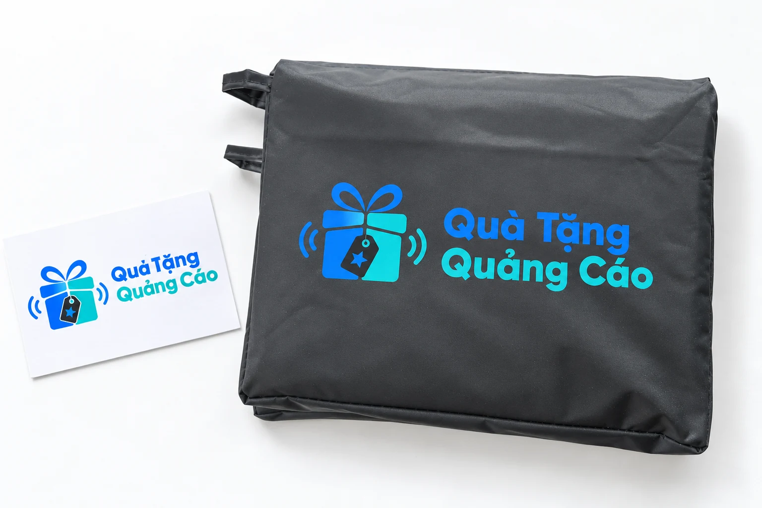 Logo Quà Tặng Quảng Cáo đề xuất trên mặt túi xám cạnh bản giấy