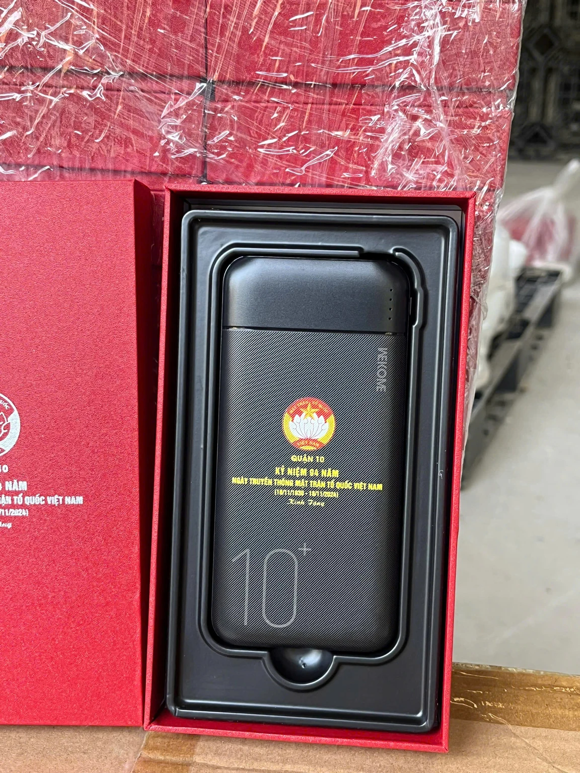 Vật phẩm màu đen có vân và phần in đỏ vàng trắng trong hộp đỏ nguồn